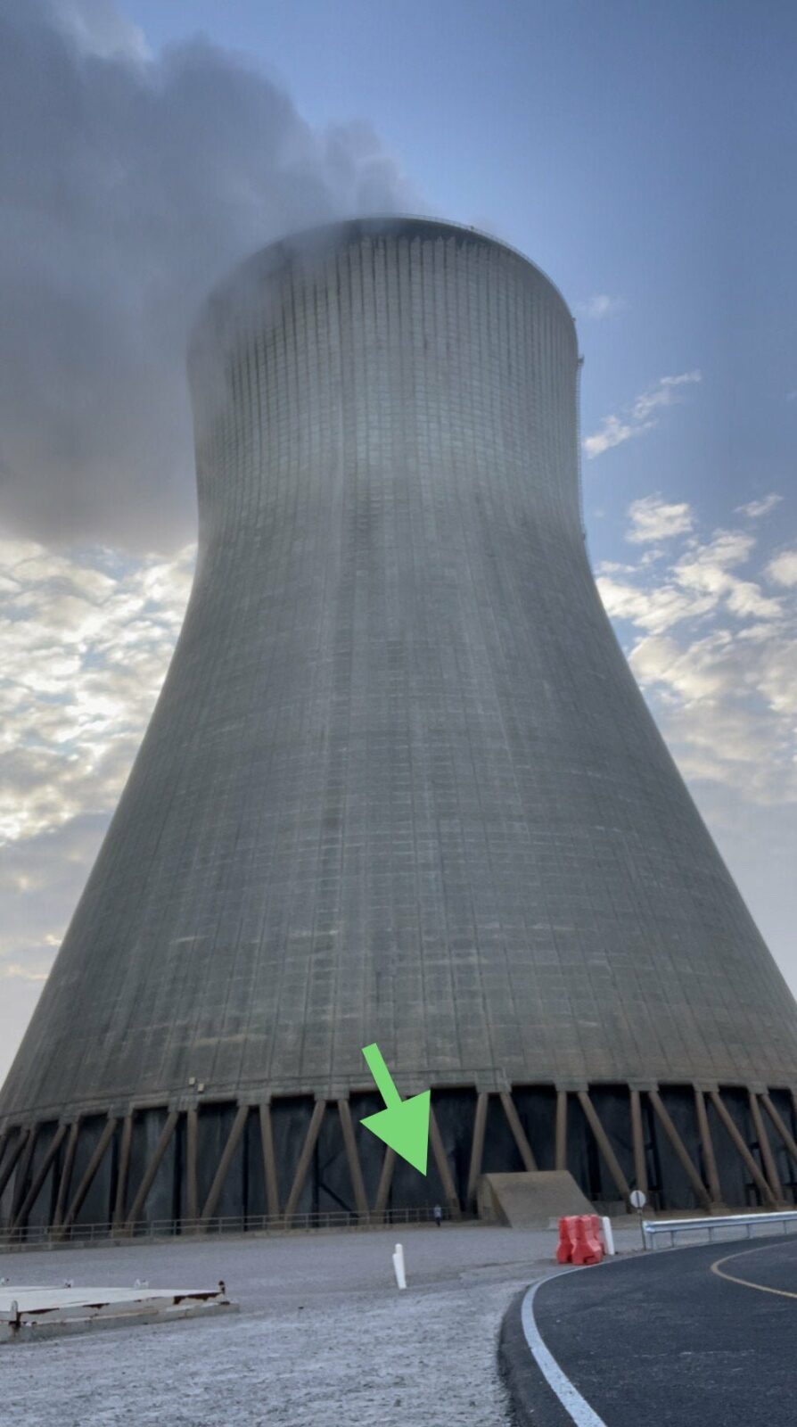 Eu em pe ao lado de uma torre de resfriamento nuclear